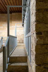 Stone staircase leading to a narrow passage framed by blue wooden doors and balustrade leading to stone wall at historical traditional bathhouse (Hamam Inal), Cairo, Egypt