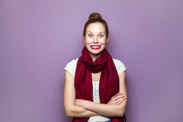 Surprised Woman. Young emotional beauty with collected hair and red scarf looking excited, crossed hands purple background. expressing positive emotions, smile with big eyes and teeth..