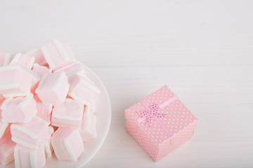 Soft pink and white marshmallow with gift box on white background. Pastel sweets.