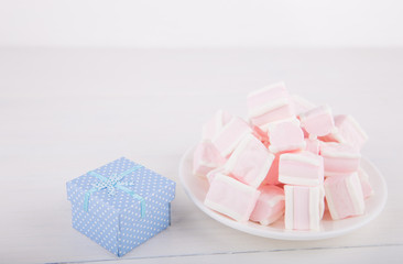 Soft pink and white marshmallow with gift box on white background. Pastel sweets.