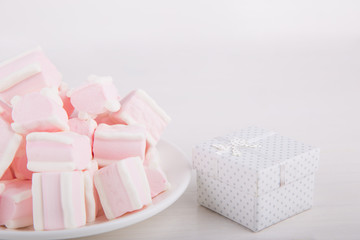 Soft pink and white marshmallow with gift box on white background. Pastel sweets.