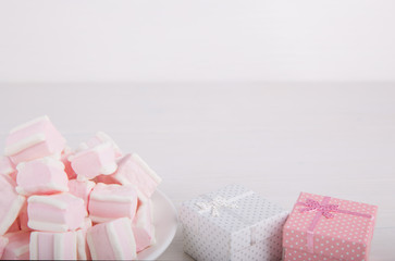 Soft pink and white marshmallow with gift boxes on white background. Pastel sweets.