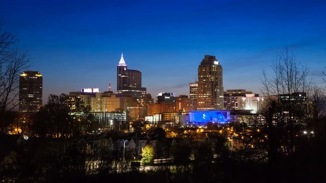 Sunrise Timelapse Over Raleigh NC City Skyline with Lit Building Exteriors in front of a Blue Sky Moving from Night to Day 