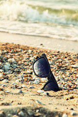 Fototapeta na wymiar Sunglasses with black frame on sandy beach.