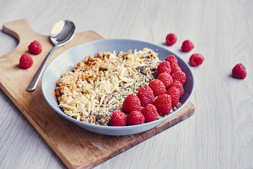 Raspberry, nuts and sunflower seed in a cup on a wooden desk.