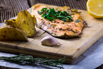 Trout with potateos on wooden board.
