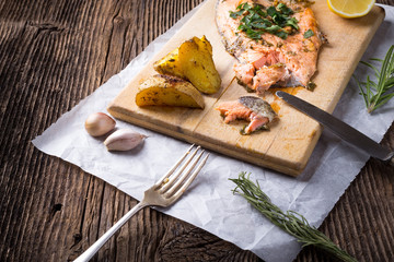 Trout with potateos on wooden board.