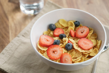 dry corn flakes with berries in bowl on table