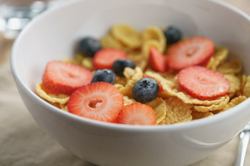 closeup of dry corn flakes with berries in bowl