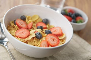 dry corn flakes with berries in bowl on table
