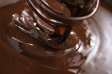 closeup of steel whisk in melted dark premium chocolate