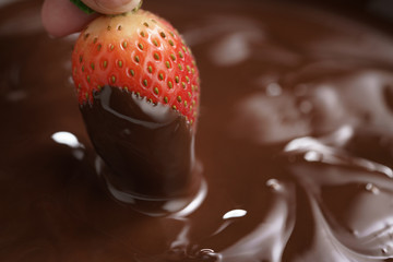dipping strawberry into dark premium chocolate