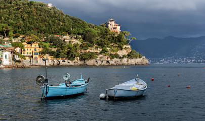 Fototapeta na wymiar Stormy sky and small boats in sea bay of Portofino town. Portofino is small fishing town in Liguria district in Italy.