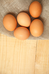 Raw organic brown eggs over linen napkin and rustic wooden background