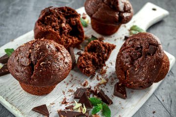 Brown muffins with dark chocolate chippings on white wooden board
