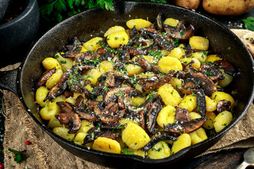 Home made potato gnocchi with mushrooms, chopped parsley and parmesan cheese in iron pan