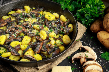 Home made potato gnocchi with mushrooms, chopped parsley and parmesan cheese in iron pan