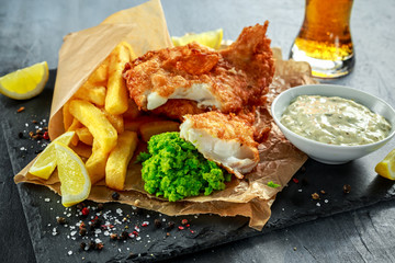 British Traditional Fish and chips with mashed peas, tartar sauce on crumpled paper with cold beer. - obrazy, fototapety, plakaty