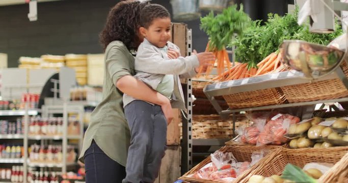 Boy picking up carrots in grocery store