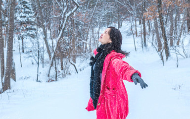 A young woman with red jacket is playing in snow