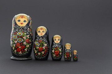 Beautiful black matryoshka dolls with white, green and red painting in front of dark background