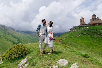 young couple in love, cuddling, a man in a suit and girl in white with flowers,