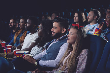 Young women and men spending free time in cinema together.