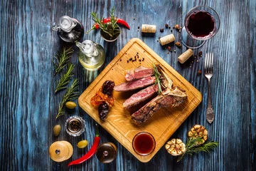 Papier Peint photo Steakhouse Sliced medium rare t-bone steak on rustic wooden background with rosemary and spices