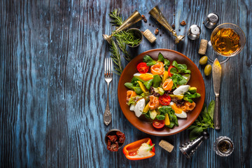 Delicious fresh salad with seafood on the old wooden background