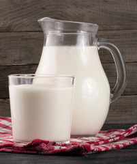 jug and glass of milk on a wooden background
