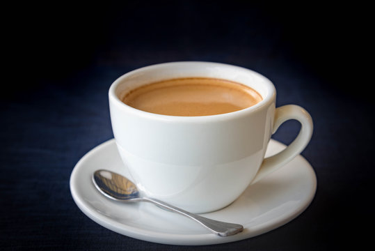 White cup of coffee on dark blue background