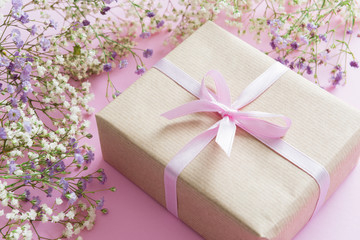 Pink background with lilac and white flowers and a present, mother's day concept