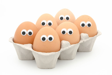six eggs in a box with googly eyes on white background