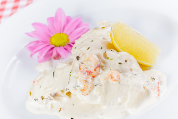 Pike Perch with cream sauce and shrimp on white plate