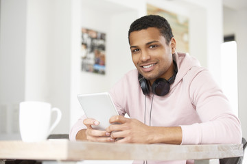 Fototapeta na wymiar Enjoy music. Shot of a handsome young Afro American man using his laptop and listening music while working at home. 