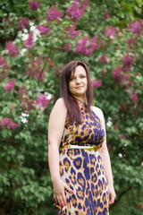 Fototapeta premium Portrait of a sexy sensual beautiful brunette girl with long hair in leopard yellow-black dress walking in the park
