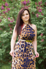 Fototapeta premium Portrait of a sexy sensual beautiful brunette girl with long hair in leopard yellow-black dress walking in the park