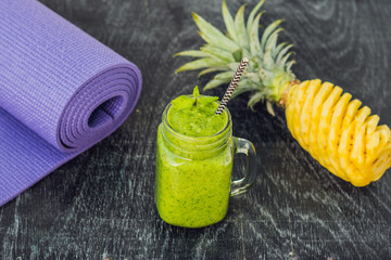 Green smoothies made of spinach and pineapple and a yoga mat. Healthy eating and sports concept
