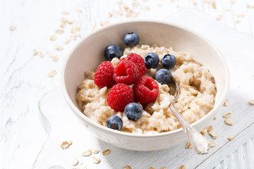 homemade oatmeal with berries on white wooden table, closeup