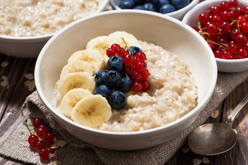 homemade oatmeal with berries on wooden background, closeup top view