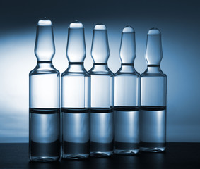 Row of ampulas with medicine on blue background