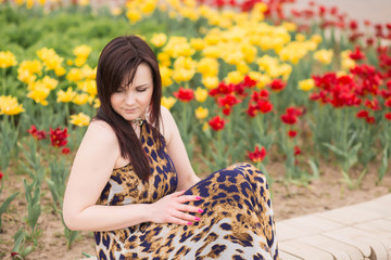 Portrait of a sexy sensual beautiful brunette girl with long hair in leopard yellow-black dress walking in the park