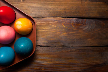 Multicolored chicken, painted eggs for the Easter holiday in box on wooden weathering background