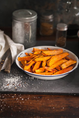 Fried Seasoned sweet Potato with Herbs on Dark Table.