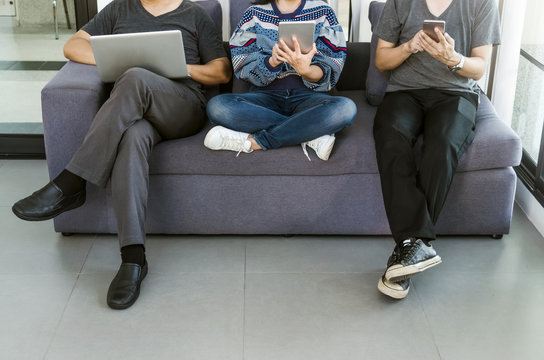 Group of friends sitting sofa using modern gadgets.