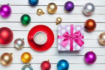 Naklejka na ściany i meble photo of red cup of coffee and cute gift near colorful baubles on the wonderful white wooden background
