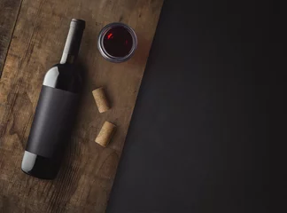 Gordijnen Bottle of red wine with label on old board. Glass of wine and cork. Wine bottle mockup. Top view. © KOSIM