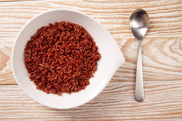 Red wild rice in a white plate over wood