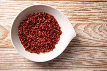 Red wild rice in a white plate over wood