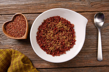 Red wild rice in a white plate over wood